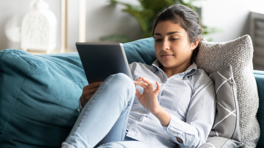 Lady on couch with tablet reading her own copywriting, checking tone of voice