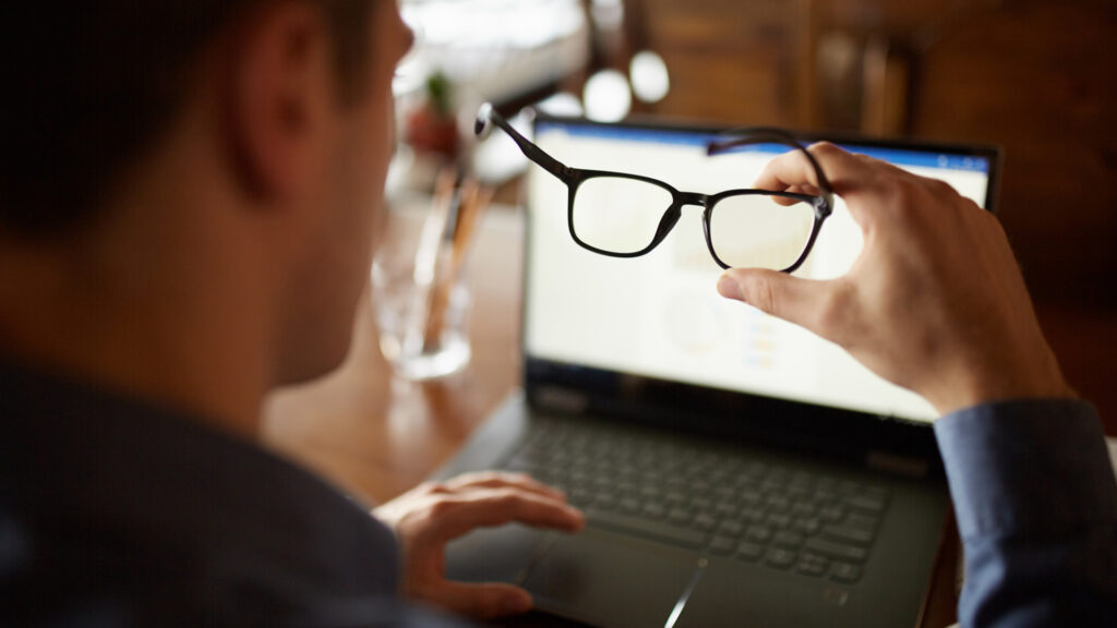 Man with glasses using laptop to unsubscribe from mailing list