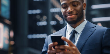 Portrait of Successful African-American Businessman reading on mobile about financial services