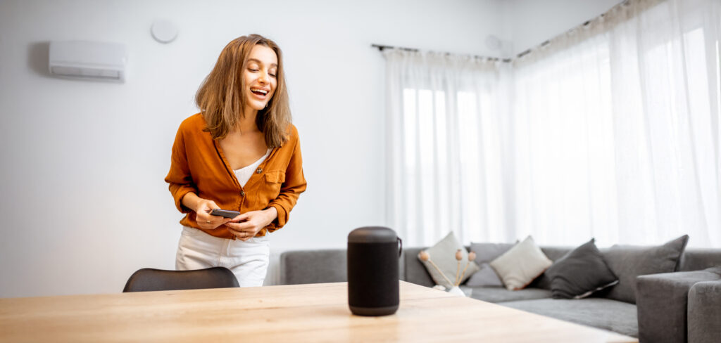 Young cheerful woman controlling home devices with natural language search